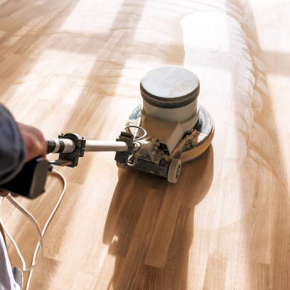 a professional master cleans the floor (parquet) with a polishing machine